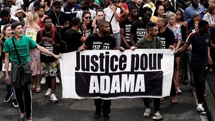 Une banderole "Justice pour Adama" tenue lors d'une manifestation&nbsp;à Beaumont-sur-Oise, le 20 juillet 2019. (KENZO TRIBOUILLARD / AFP)