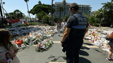 Un policier municipal se recueille sur la promenade des Anglais à Nice (Alpes-Maritimes), le 25 juillet 2016. (CITIZENSIDE/ROLAND MACRI / CITIZENSIDE / AFP)