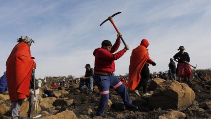 Une femme creuse&nbsp;à la recherche de ce qu'elle pense être des diamants après la découverte de pierres non identifiées dans le village de KwaHlathi près de Ladysmith, en Afrique du Sud, le 15 juin 2021.&nbsp; (PHILL MAGAKOE / AFP)