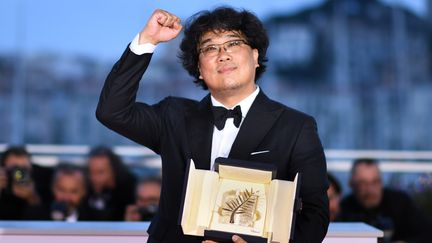 Le cinéaste Bong Joon-Ho peut brandir le poing... C'est la première fois qu'une Palme d'or est attribuée à un sud-coréen. Son nouveau film, Parasite, est à découvrir en salles dès le 5 juin 2019. (LOIC VENANCE / AFP)