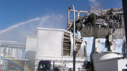 Des liquidateurs d&eacute;versent de l'eau sur le r&eacute;acteur 3 de la centrale de Fukushima (Japon), le 18 mars 2011. (TEPCO / AFP)