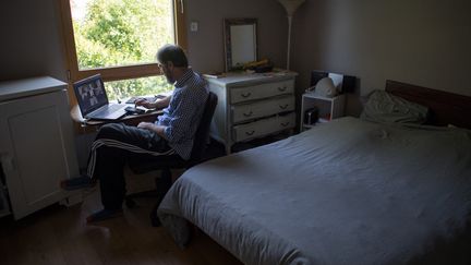 Un homme en plein télétravail dans sa chambre. Photo d'illustration. (LOIC VENANCE / AFP)