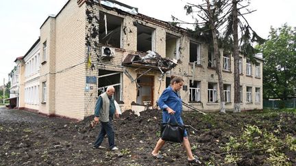 Des habitants passent devant un immeuble partiellement détruit par des frappes dans la ville de Chuguiv, à l'est de Kharkiv (Ukraine), le 16 juillet 2022.&nbsp; (SERGEY BOBOK / AFP)