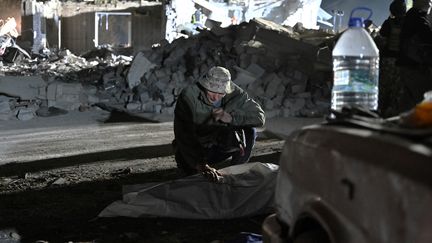 Un habitant du village de Groza, en Ukraine, se recueille devant la dépouille de sa femme morte dans la frappe russe qui a fait au moins 51 morts, le 5 octobre 2023. (GENYA SAVILOV / AFP)