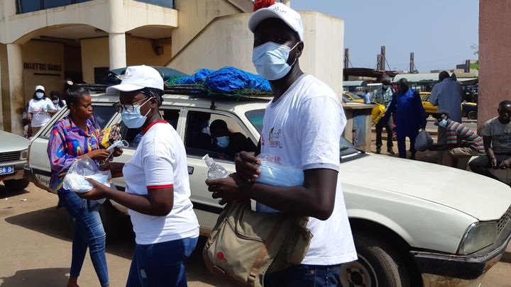 A la gare routière des Baux Maraichers de Dakar (Sénégal), des jeunes distribuent des masques et du gel hydroalcoolique aux voyageurs qui n'en ont pas.&nbsp; (OMAR OUAHMANE / RADIO FRANCE)