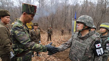 Deux militaires représentant les deux Corées sont sur le point de se serrer la main, le 22 novembre 2018, sur la frontière, dans&nbsp;la Zone démilitarisée. (SOUTH KOREAN DEFENCE MINISTRY / AFP)