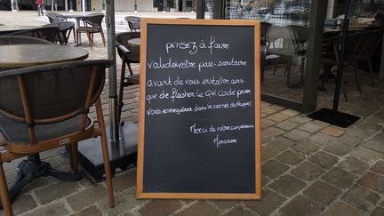 Un panneau indique que le pass sanitaire est obligatoire pour manger à la brasserie Honorine de Deauville (Calvados), dimanche 25 juillet. (CELINE AUTAIN / RADIO FRANCE)