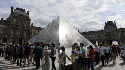 Des touristes font la queue autour de la Pyramide du Louvre le 19 juillet 2019. (ALAIN JOCARD / AFP)