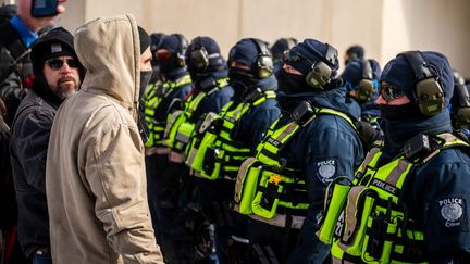 Des policiers canadiens font face à des opposants aux restrictions sanitaires, vendredi 18 février 2022 à Ottawa. (ANDREJ IVANOV / AFP)