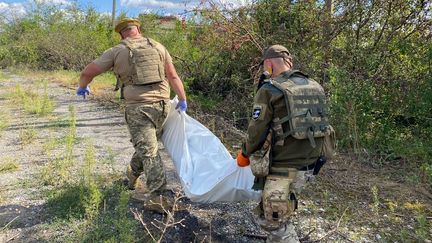 Maxim et Volodymyr, deux soldats ukrainiens, transportent le corps d'un soldat russe dans un sac mortuaire. (BORIS LOUMAGNE / FRANCEINFO / RADIO FRANCE)