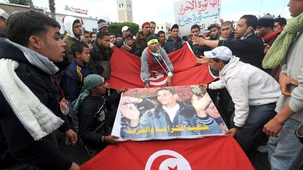 Des habitants de Kasserine portent une affiche de Mohamed Bouazizi, devant le palais du gouvernement à Tunis, le 28&nbsp;janvier 2011. (FETHI BELAID / AFP)