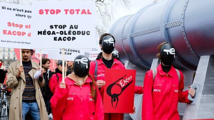 Des manifestants protestent contre le projet EACOP de TotalEnergies, le 12 mars 2022 à Paris. (VINCENT KOEBEL / NURPHOTO / AFP)