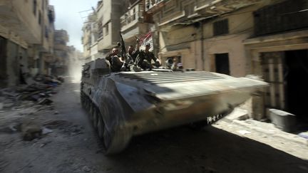 Des soldats syriens, fid&egrave;les au r&eacute;gime, patrouillent &agrave; bord d'un char dans un quartier de Homs (Syrie) d&eacute;vast&eacute; par les combats, le 31 juillet 2013. (JOSEPH EID / AFP)