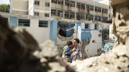 Un homme &eacute;vacue un enfant apr&egrave;s la destruction d'une &eacute;cole de l'ONU servant de refuge pour les palestiniens, le 30 juillet 2014 &agrave; Gaza. (© SUHAIB SALEM / REUTERS / X90014)