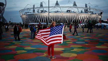 Une supporter am&eacute;ricaine pose avec le drapeau national devant le stade olympique.&nbsp; (GUILLAUME BAPTISTE / AFP)