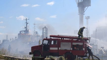 Des&nbsp;pompiers ukrainiens luttant contre l'incendie d'un bateau après des frappes russes sur le port d'Odessa, le 23 juillet 2022. (STR / ODESSA CITY COUNCIL TELEGRAM CHA / AFP)