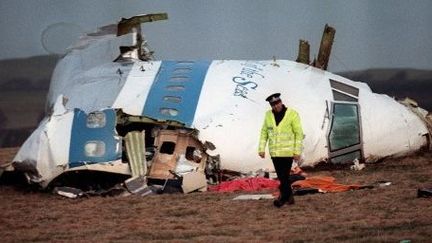 Policier devant les restes du cockpit du boeing 747 de la Pan Am qui s'est écrasé à Lockerbie (Ecosse), le 22 décembre 1988. L'attentat avait fait 270 morts, dont onze habitants de la cité écossaise. (ROY LETKEY / AFP)