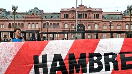 Un manifestant derrière une banderole «faim» devant le Palais du gouvernement, le 12 Décembre 2001, à Buenos Aires. ( AFP PHOTO/FABIAN GREDILLAS)