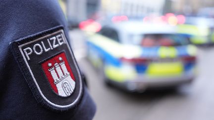 Un policier se tient devant un véhicule de police à Hambourg (Allemagne), le 15 mars 2024. (MARCUS BRANDT / DPA)