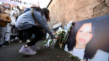 Une jeune femme dépose des roses blanches devant le collège Jean-Henri Lambert, lors d'une marche blanche à Mulhouse (Haut-Rhin), le 24 octobre 2021. (FREDERICK FLORIN / AFP)