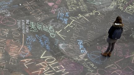 Une femme au milieu des messages de solidarité écrits sur le sol, place de la Bourse, après les attentats de Bruxelles, mardi 22 mars 2016.&nbsp; (KENZO TRIBOUILLARD / AFP)