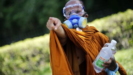 Un moine bouddhiste porte un masque &agrave; gaz lors d'affrontements avec la police &agrave; Bangkok&nbsp;(Tha&iuml;lande), le 2 d&eacute;cembre 2013. (DAMIR SAGOLJ / REUTERS)