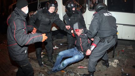 Des policiers rel&egrave;vent un homme bless&eacute; lors d'affrontements &agrave; Donetsk (Ukraine), le 13 mars 2014. (ALEXANDER KHUDOTEPLY / AFP)