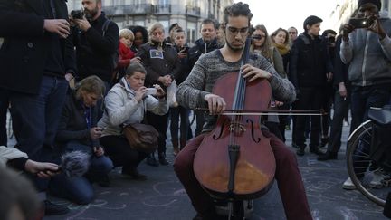 Un homme joue du violoncelle au mémorial improvisé place de la Bourse à Bruxelles, après les attentats qui ont touché la capitale belge mardi 22 mars 2016. (KENZO TRIBOUILLARD / AFP)