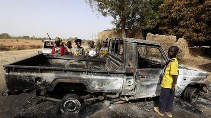 Des Maliens observent un v&eacute;hicule incendi&eacute; appartenant &agrave; des islamistes, apr&egrave;s le passage des troupes fran&ccedil;aises &agrave; Diabali, le 24 janvier 2013. (ERIC GAILLARD  / REUTERS)