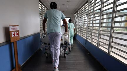 Une infirmière emmène un patient atteint du Covid-19 vers l'unité de soins intensifs du&nbsp;Centre hospitalier universitaire de Saint-Pierre de La Réunion. (RICHARD BOUHET / AFP)