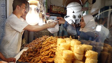 Une femme achète des pâtisseries traditionnelles pendant le ramadan, à Tunis, le 2 juin 2017. Image d'illustration. (MOHAMED MESSARA / EPA)