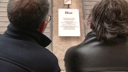 Les deux anciens musiciens de Carte de séjour, Jérôme Savy et Mokhtar Amini, devant la plaque posée sur un immeuble de Lyon (France 3 Aura)