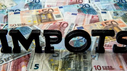 Le mot "IMPOTS" sur des billets de banque. (PHILIPPE HUGUEN / AFP)