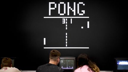 Des joueurs devant le jeu vidéo Pong, créé en 1972.&nbsp;A Cologne en 2019. (INA FASSBENDER / AFP)