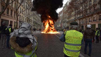 Des manifestants observent un feu boulevard Haussmann à Paris, lors de la journée de mobilistaion des "gilets jaunes", le 8 décembre 2018. (ANTONI LALLICAN / HANS LUCAS)