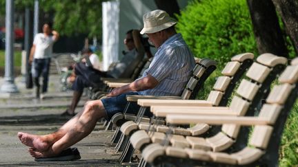 Un homme assis sur un banc, en pleine vague de chaleur, à Tokyo, au Japon, en juin 2022. (KAZUHIRO NOGI / AFP)