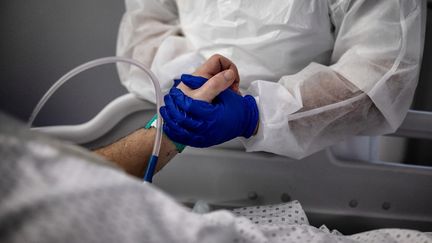 Une infirmière auprès d'un patient atteint du Covid-19 dans le service de réanimation de l'hôpital Lyon-Sud à Pierre-Benite (Rhône), le 25 janvier 2021. (JEFF PACHOUD / AFP)