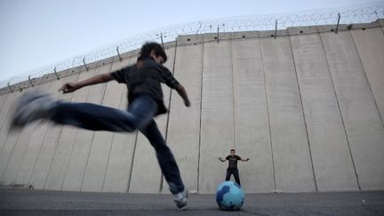 Novembre 2012. Des enfants palestiniens jouent au foot devant le mur de séparation dans le village palestinien d'Abu Dis, dans la banlieue de Jérusalem.  (AHMAD GHARABLI / AFP)