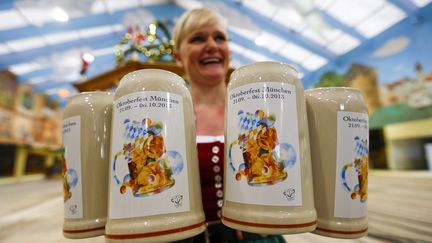 Une serveuse pr&eacute;sente les chopes de bi&egrave;re officielles de l'Oktoberfest, la f&ecirc;te de la bi&egrave;re &agrave; Munich (Allemagne), le 27 ao&ucirc;t 2013. (MICHAEL DALDER / REUTERS)