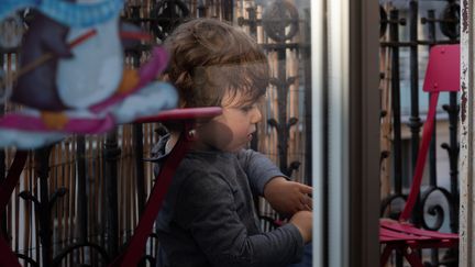 Un bébé joue sur un balcon à Paris, le 17 avril 2020.&nbsp; (RICCARDO MILANI / HANS LUCAS / AFP)