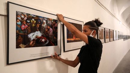 Accrochage de l'exposition "La révolution du printemps en Birmanie" réalisée par un photographe qui a tenu à rester anonyme, à la 33e édition du festival Visa pour l'Image à Perpignan, le 25 août 2021. (RAYMOND ROIG / AFP)