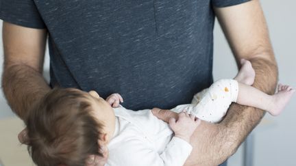 Un&nbsp;père et son bébé à leur domicile de Charenton-le-Pont le 13 avril 2021. (CAMILLE CIER / HANS LUCAS)