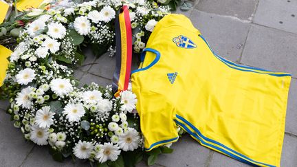 Un maillot de l'équipe de football suédoise déposée sur une couronne de fleurs en hommage aux victimes de l'attentat de Bruxelles (Belgique), le 18 octobre 2023. (BENOIT DOPPAGNE / BELGA MAG / AFP)