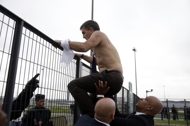 Le directeur des ressources humaines d'Air France, Xavier Broseta, quitte le si&egrave;ge de la compagnie en escaladant une barri&egrave;re &agrave; Roissy (Val-d'Oise), le 5 octobre 2015. (KENZO TRIBOUILLARD / AFP)