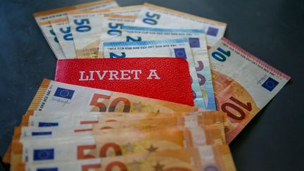 Un livret A est photographié avec des billets de banque, le 16 avril 2020, à Valence (Drôme). (NICOLAS GUYONNET / HANS LUCAS / AFP)