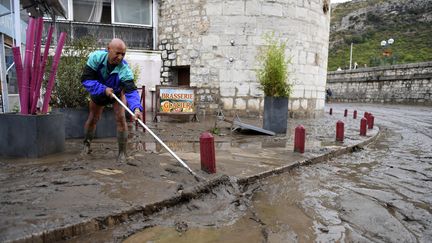 Un habitant déblaie la boue dans une rue d'Anduze (Gard), le 19 septembre 2020. (NICOLAS TUCAT / AFP)