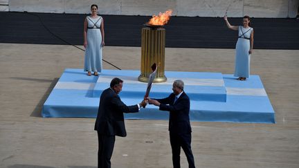 Le Président du comité olympique hellénique Spyros Kapralos a donné une lanterne contenant la flamme au vice-président du comité d'organisation Pékin-2022 Yu Zaiqing, le mardi 19 octobre 2021. (LOUISA GOULIAMAKI / AFP)