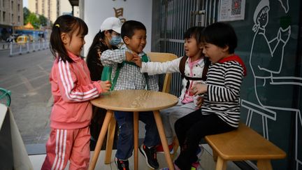 Des enfants jouent à l'extérieur d'un café à Pékin (Chine), le 11 mai 2021. (GREG BAKER / AFP)