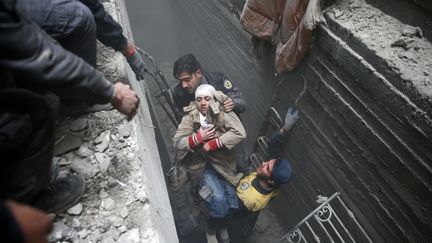 La protection civile vient en aide à une jeune femme inconsciente, réfugiée dans un abris à Douma, dans la Ghouta orientale, le 22 février 2018.&nbsp; (BASSAM KHABIEH / REUTERS)