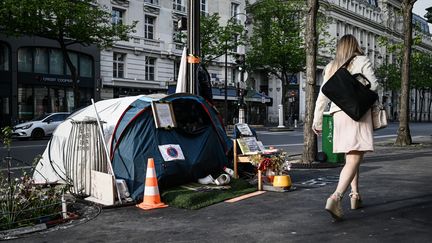 Une femme passe devant la tente d'un sans-abri à Paris, le 16 avril 2020. (PHILIPPE LOPEZ / AFP)